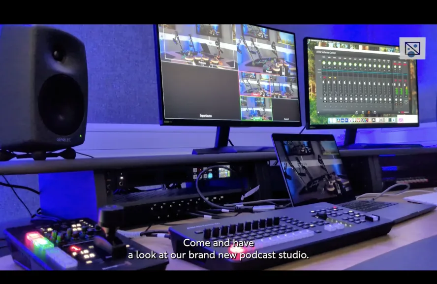 Podcast studio edit desk with sound mixers and two monitors at Ravensbourne University lit with purple light