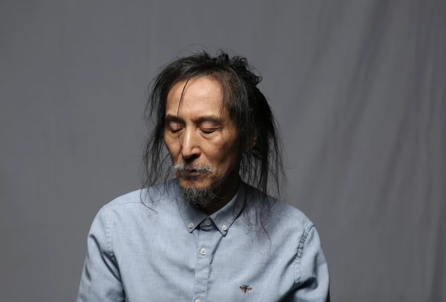 portait of a man with long hair and a beard eyes closed