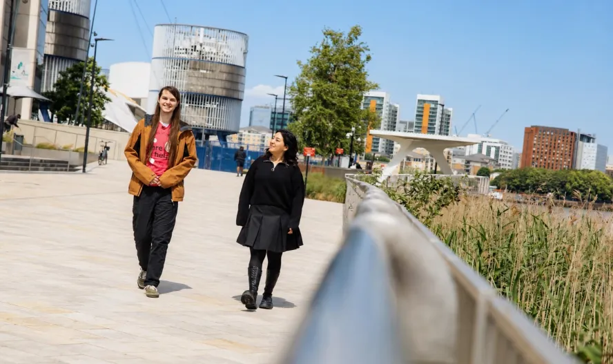 Students walking along riverside laughing