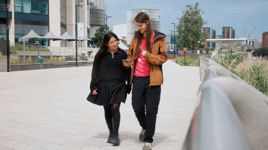 Students walking and laughing along riverside 