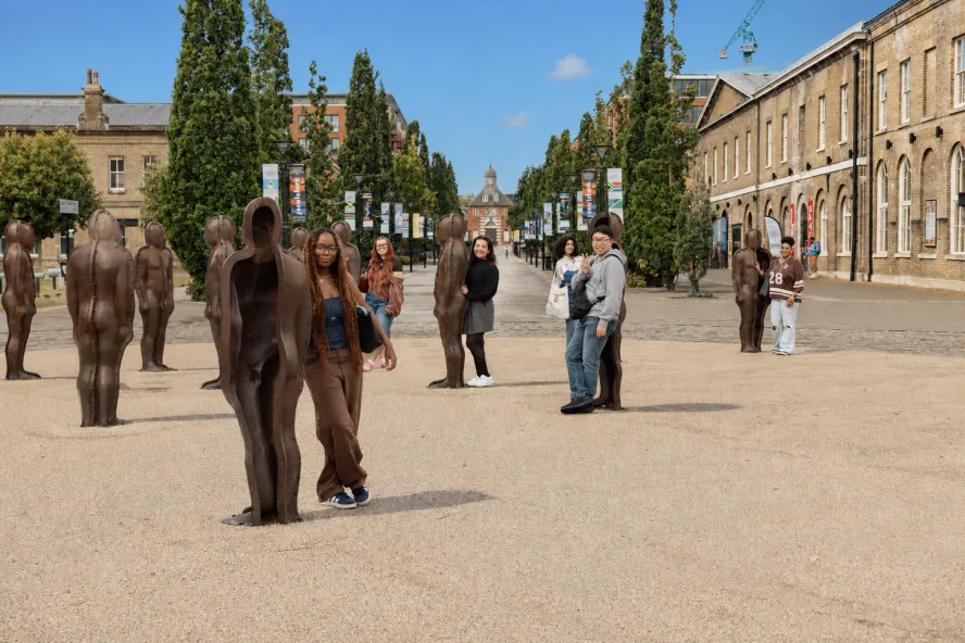 Students posing next to statues