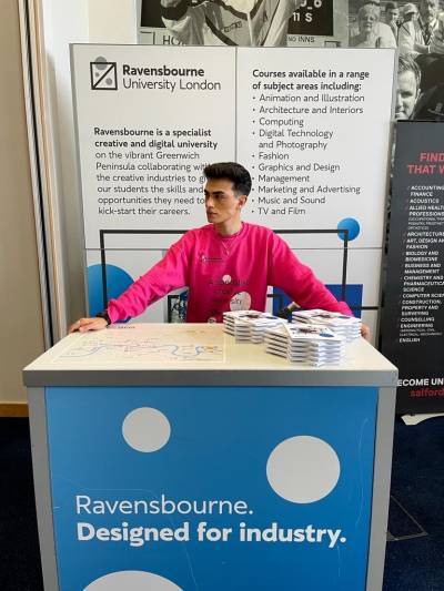 Man behind a Ravensbourne Uni stand at an exhibition