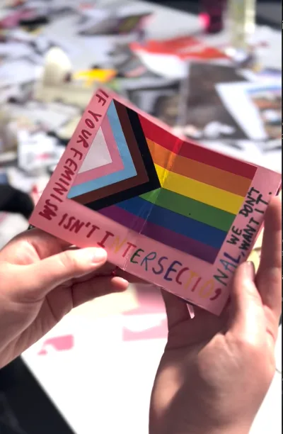 A small pink booklet with the rainbow pride flag with handwritten words around saying "intersectional"