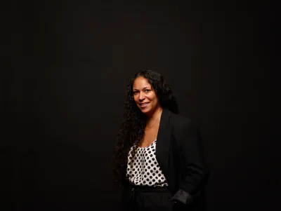 Woman wearing a blazer and polka dot top smiles at the camera