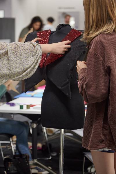 2 sets of hand draping sparkly red fabric on the mannequin