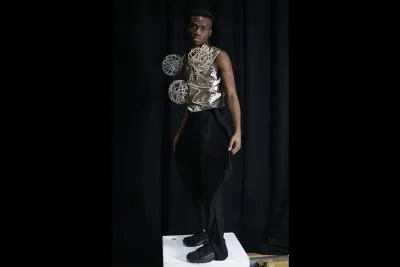 Model poses in a gold top with orbs and black trousers
