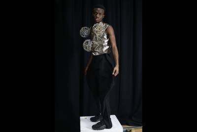 Model poses in a gold top with orbs and black trousers