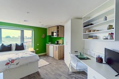 Inside The Cube student accommodation premium plus studio. A spacious and bright room with a bed, desk area, kitchen area and large window..