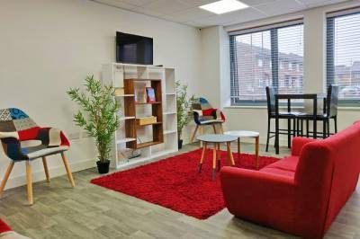 Inside the communal space of The Cube, a sofa, table and chairs shelves and a TV on the wall.
