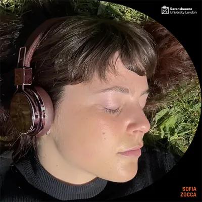 Close up of a young woman lying on the grass with headphones