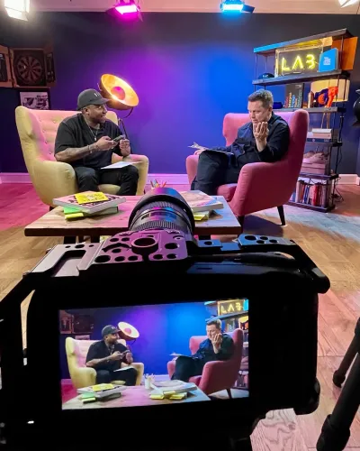 View of two men sat on armchairs talking seen through a camera