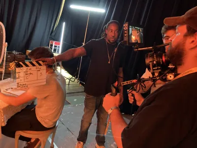 Image shows behind the scenes filming with man holding clapper board