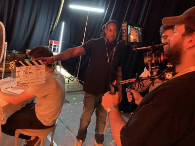 Image shows behind the scenes filming with man holding clapper board