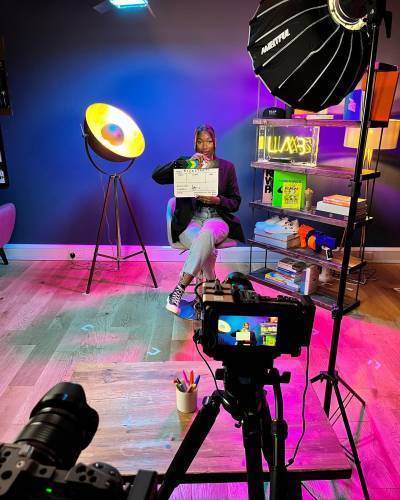 Woman sits in front of camera holding clapper board 