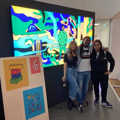 Three individuals pose in front of large animation 