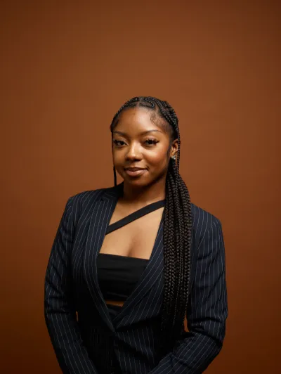 Véronique smiling at the camera wearing a black pin striped suit.