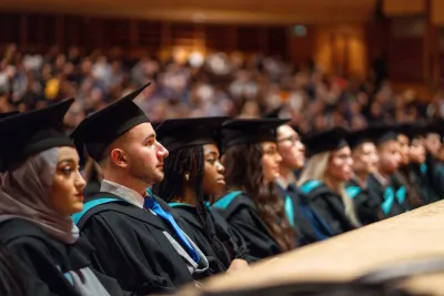 Group of graduates sit in crowd at graduation