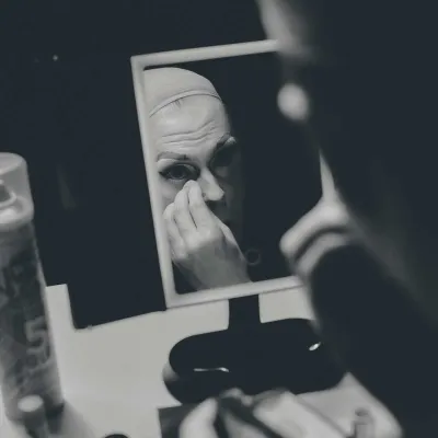 A performer applying makeup in a mirror 