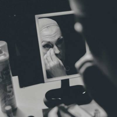 A performer applying makeup in a mirror