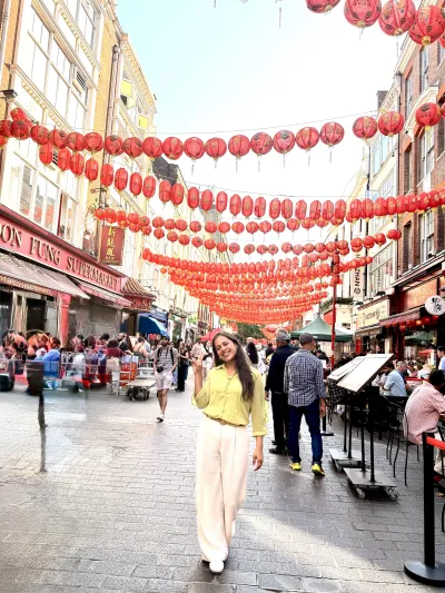 A smiling woman posing in front of the laterns in London's Chinatown