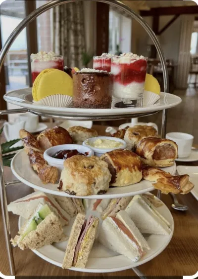 A cake stand with various afternoon tea foods on each level - including cakes, desserts, scones, sandwiches